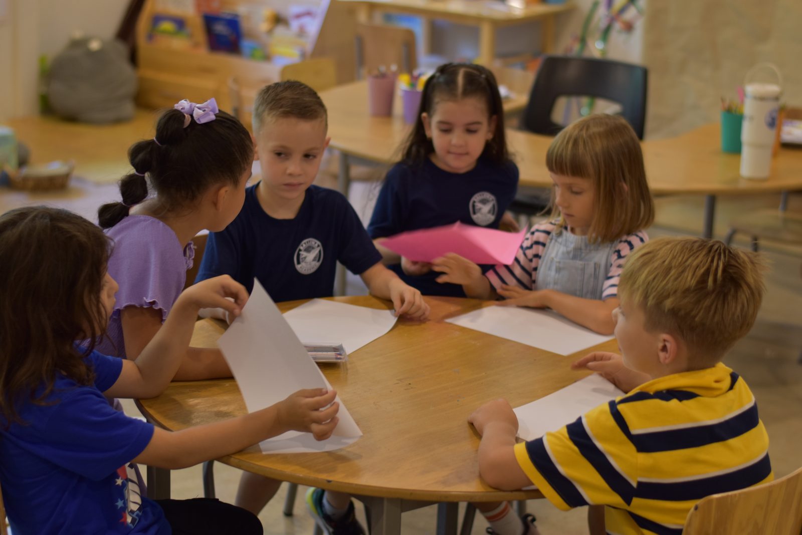 Young students working with pink paper and materials at a table