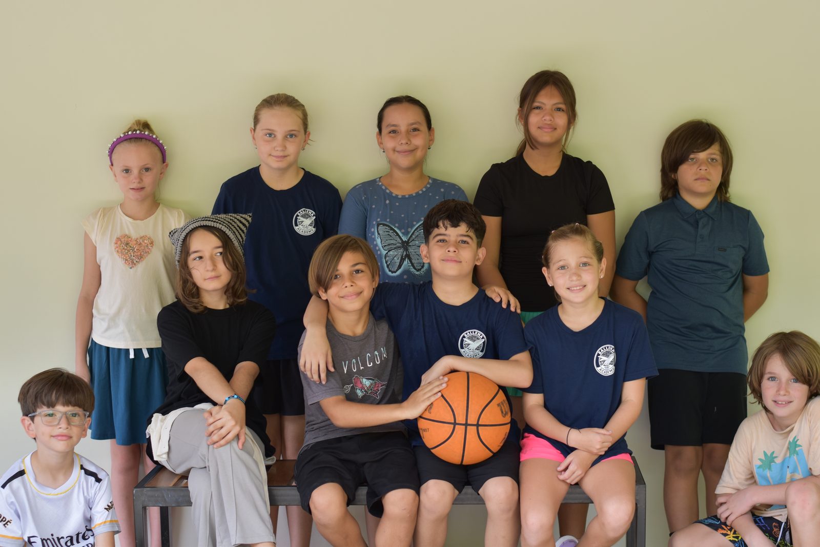 Diverse group of students arranged in classroom, some holding a basketball