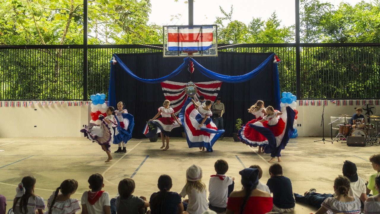 Teacher and children performing on gymnasium floor with Costa Rican flag