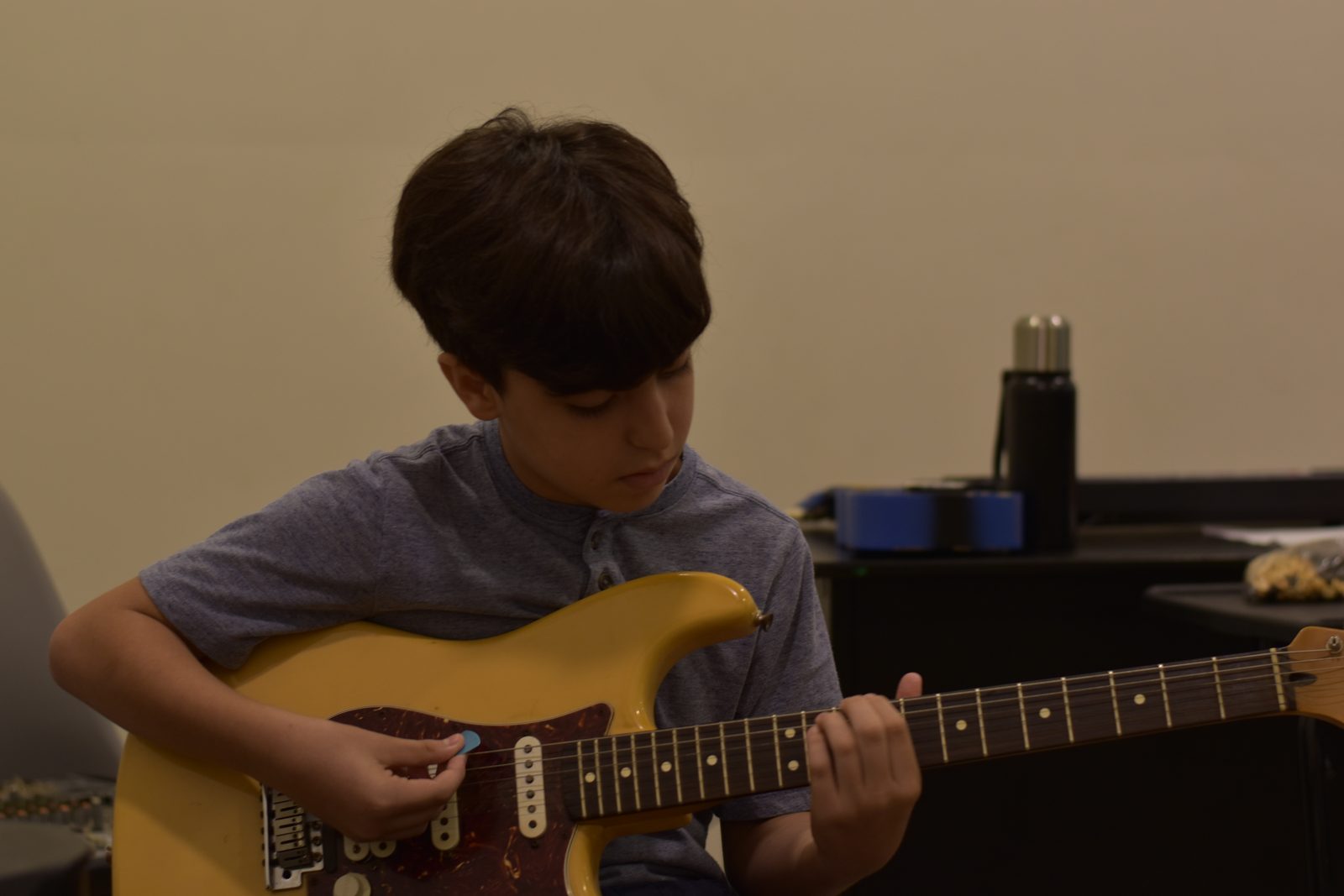 Young boy concentrating while playing a yellow electric guitar in classroom