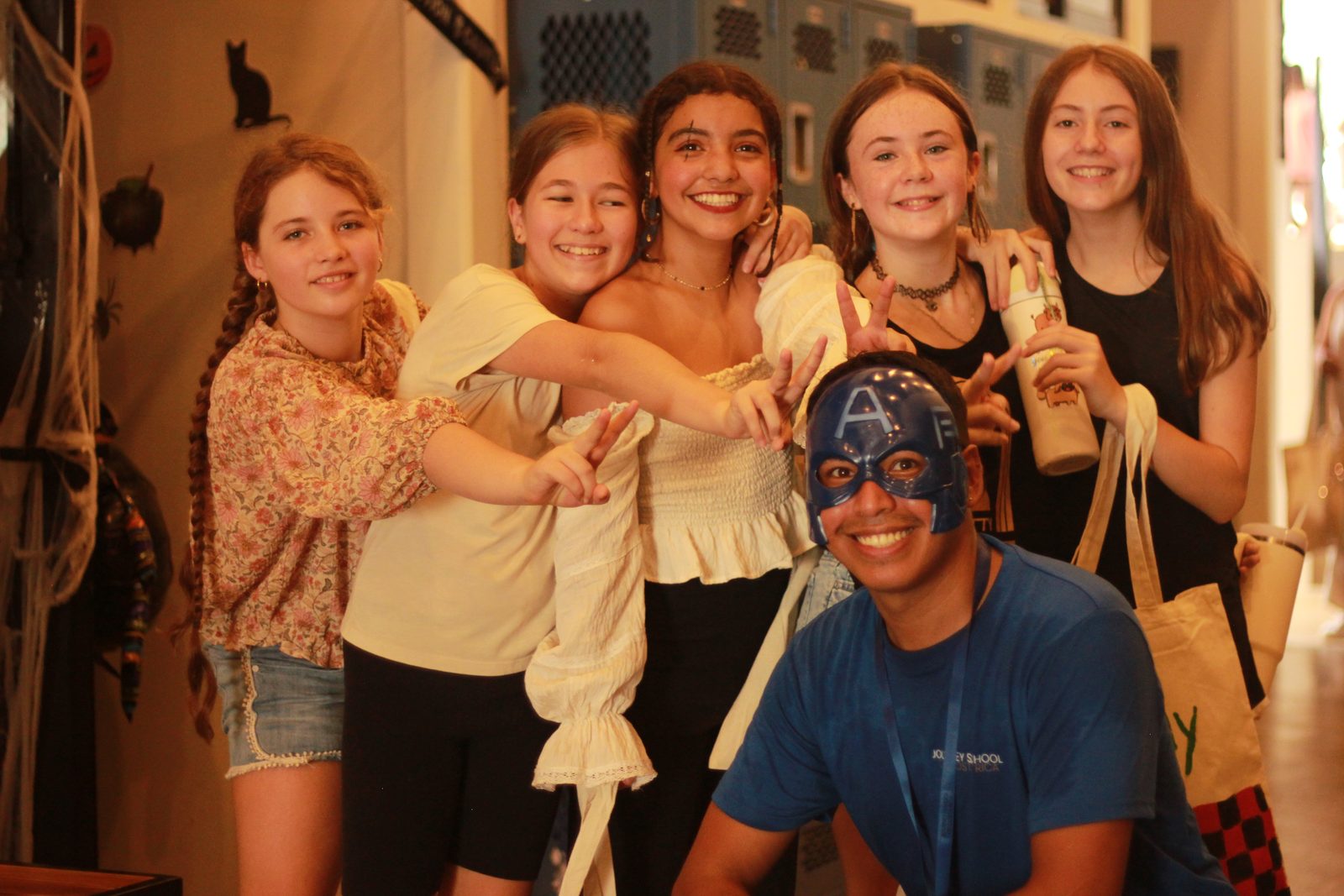 Group of students and teacher posing together indoors holding up pasta decorations