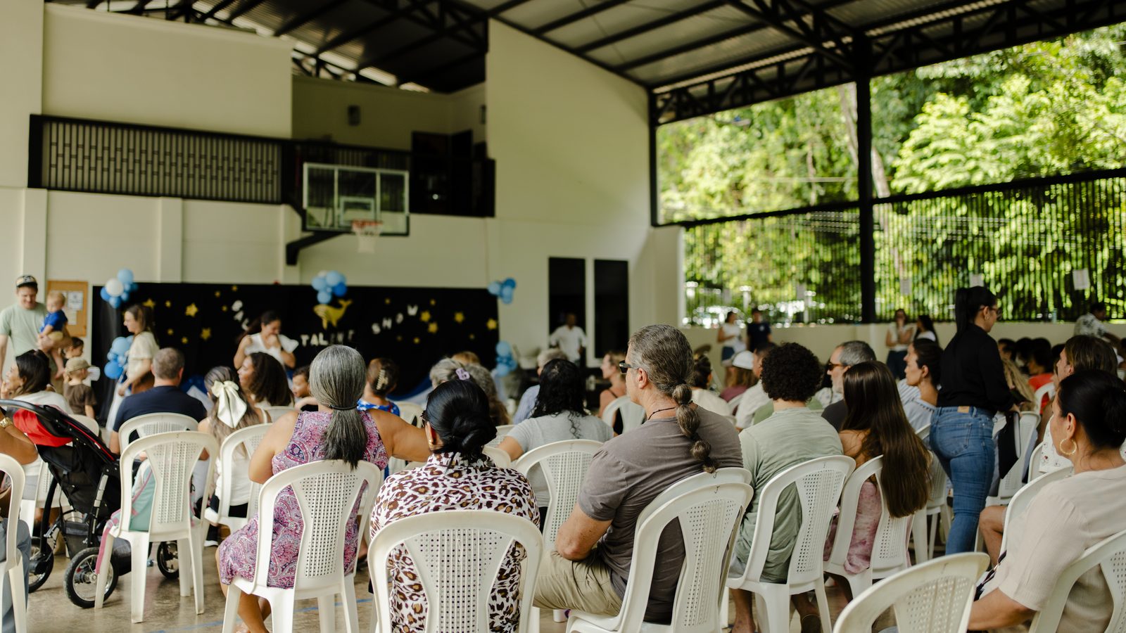Large school assembly with families and community watching performance on stage