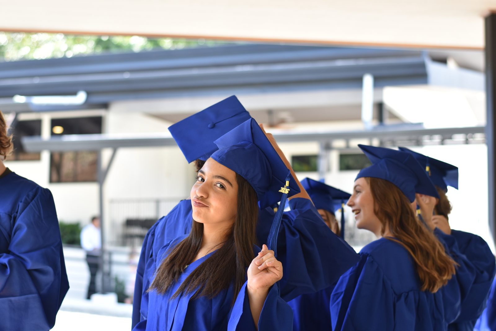 Female students in blue graduation gowns look upward at graduation ceremony