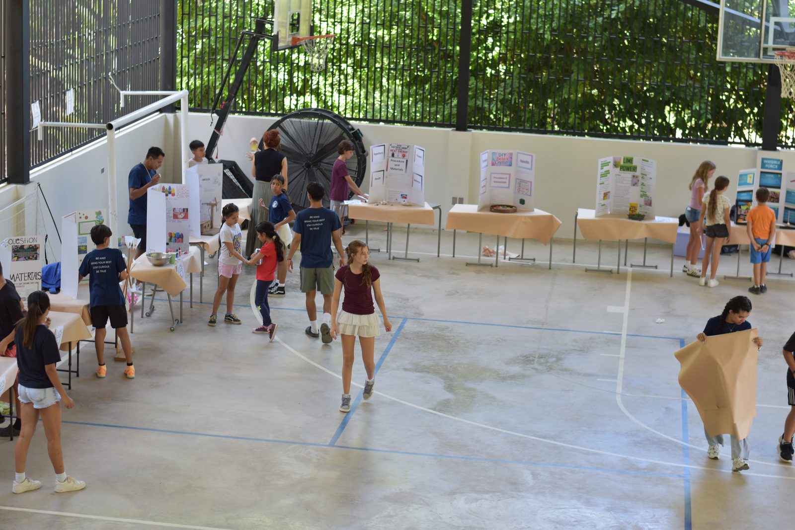 Students present science projects at outdoor exhibition with posters