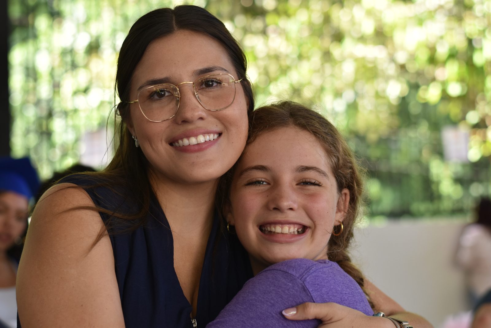 Teacher and student embrace with bright smiles in jungle surroundings