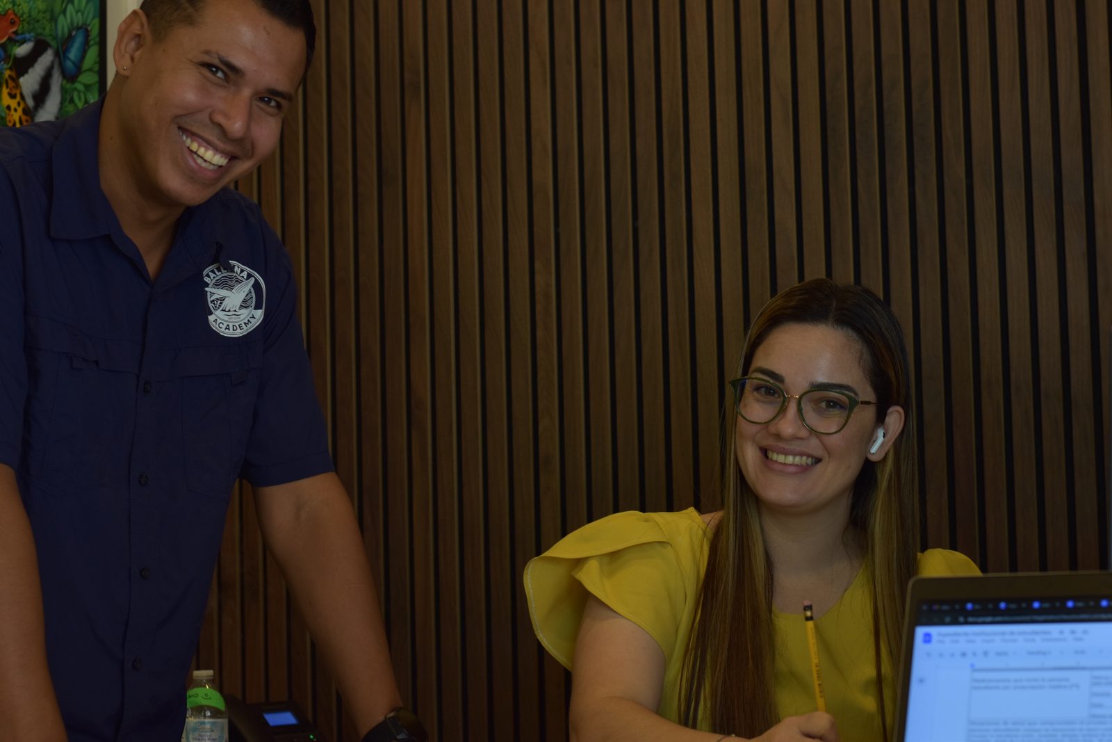 Two secondary students smile while working together at computer