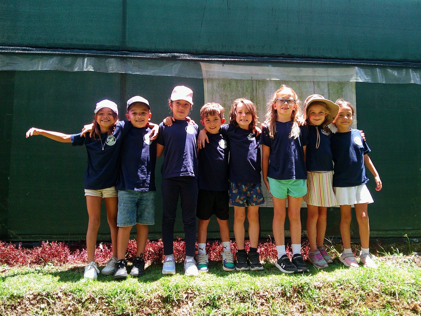 Row of smiling primary students in uniform stand together linking arms