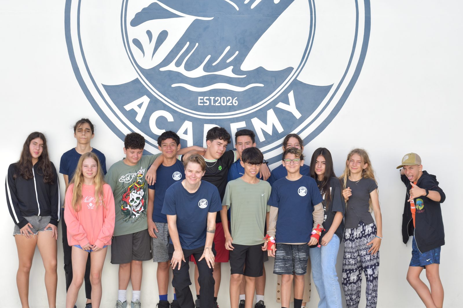 Secondary students gather for group photo in front of school logo